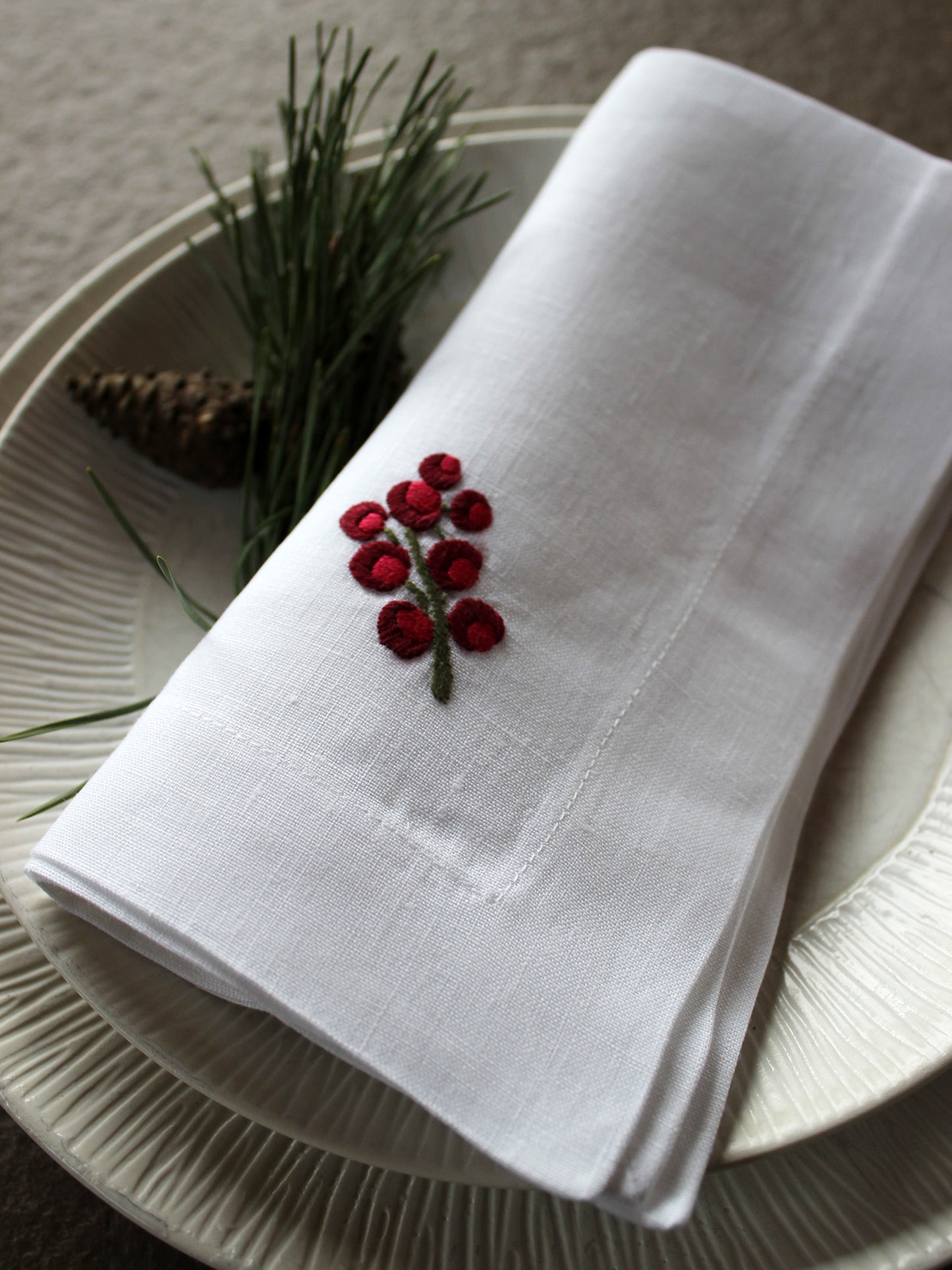 mit Beeren bestickte Stoffserviette aus Leinen von Indradanush auf Teller