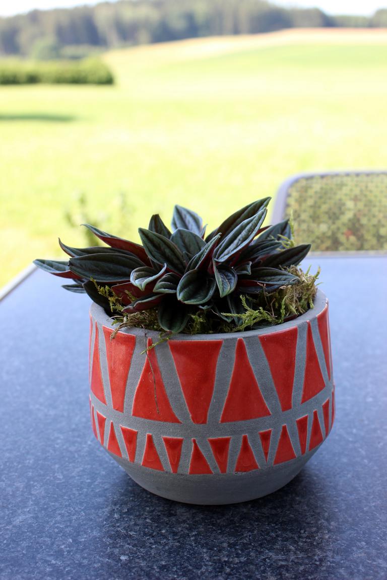 Bunte Übertöpfe in rot geometrisch aus Ton auf Tisch dekoriert