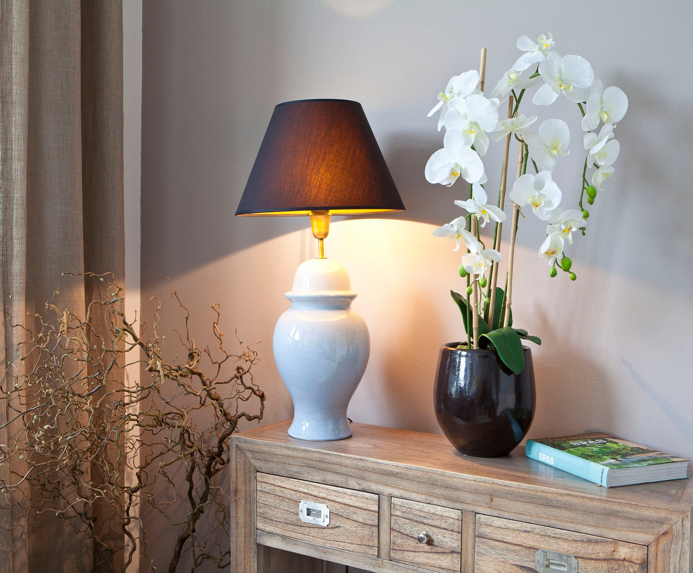weiße, bauchige Lampe aus Keramik auf Sideboard im Wohnzimmer