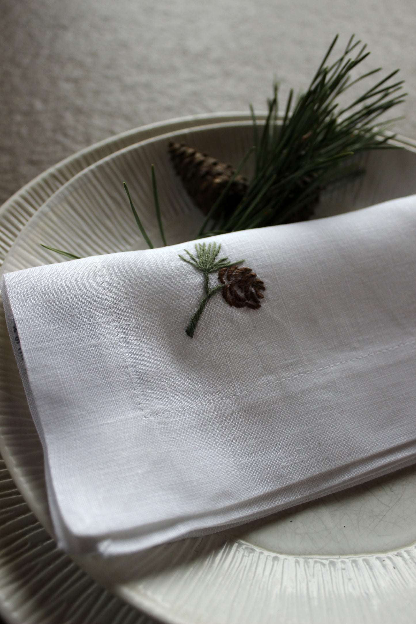 weiße Serviette aus Stoff in Größe 40 x 40 cm mit Motiv Zweig und Zapfen