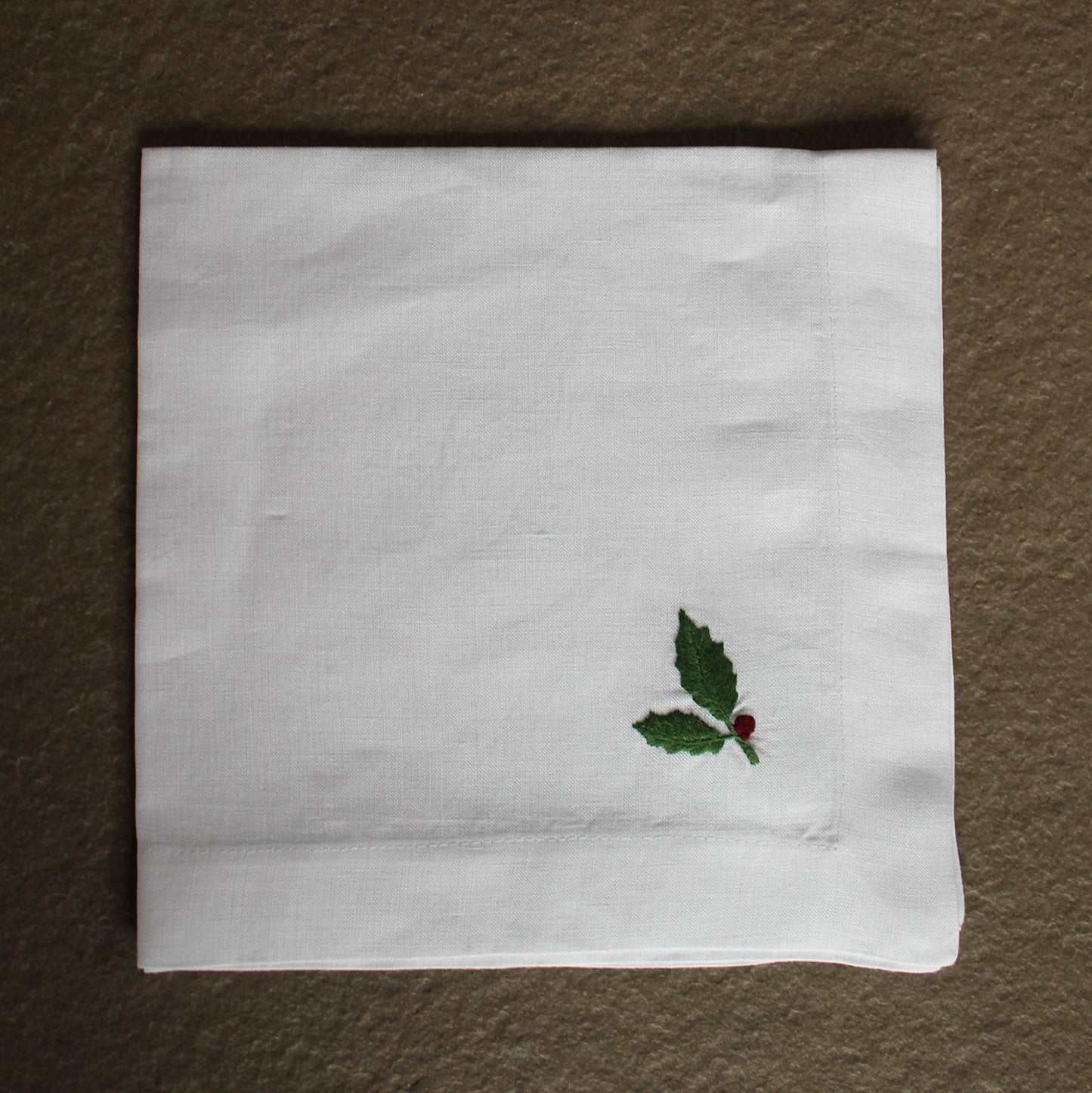 Serviette in weißem Leinen handbestickt mit Ilex in rot und grün