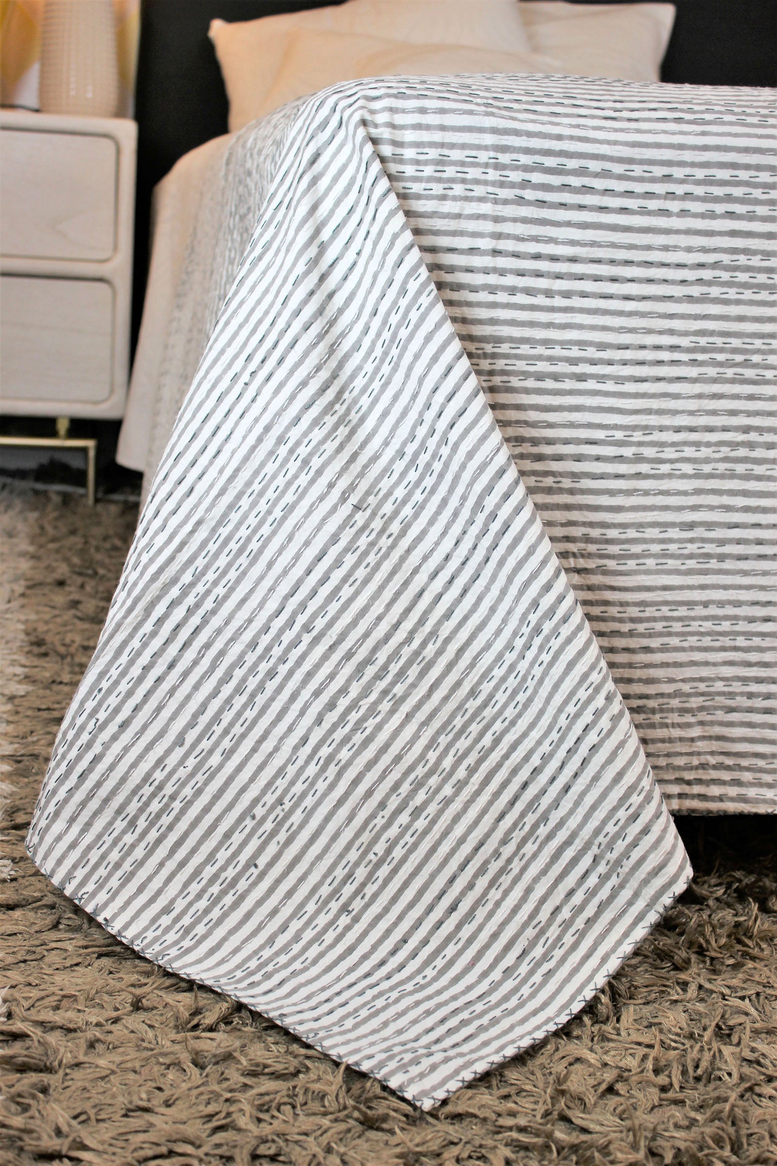graue weiße Tagesdecke handgemacht in Fairetrade auf Bett dekoriert