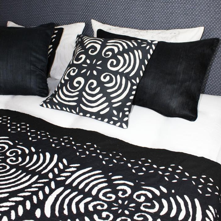 mit schwarz weißen Kissen und Decke dekoriertes Bett