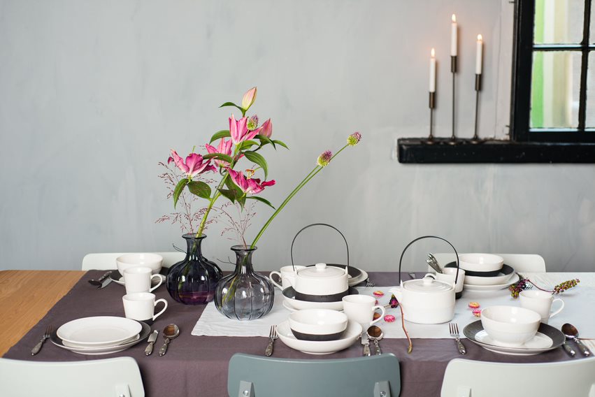 Keramiktassen und Teller auf Tisch gedeckt